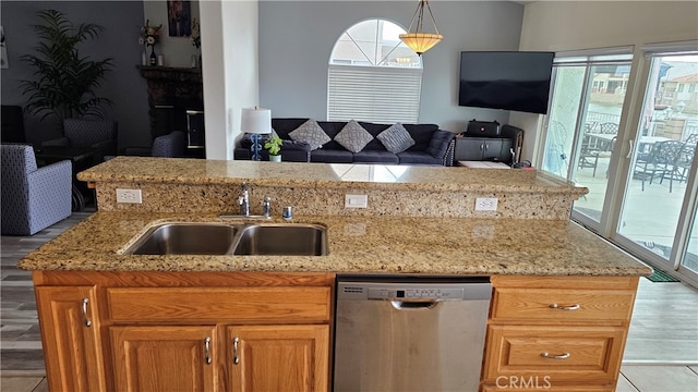 kitchen with sink, decorative light fixtures, stainless steel dishwasher, and light hardwood / wood-style flooring