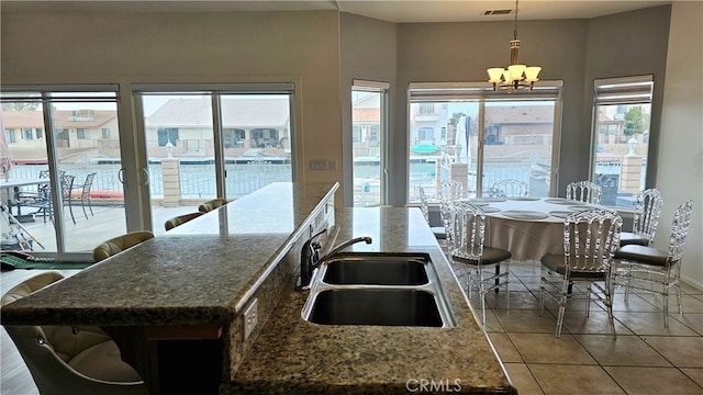 kitchen featuring a kitchen island, sink, tile patterned floors, a notable chandelier, and hanging light fixtures