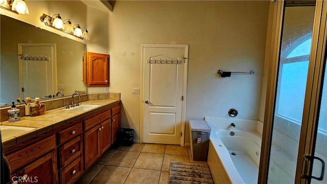 bathroom featuring tiled tub, vanity, and tile patterned flooring