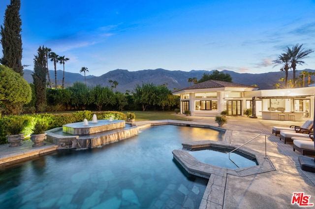 view of pool featuring an in ground hot tub, a mountain view, pool water feature, and a patio area