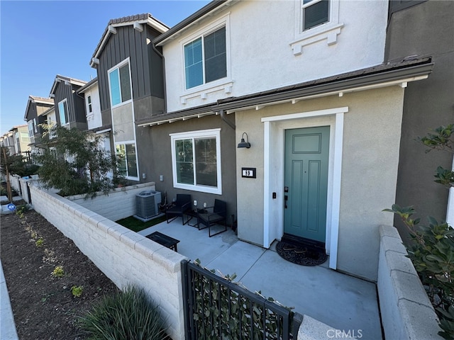 view of exterior entry featuring cooling unit and a patio