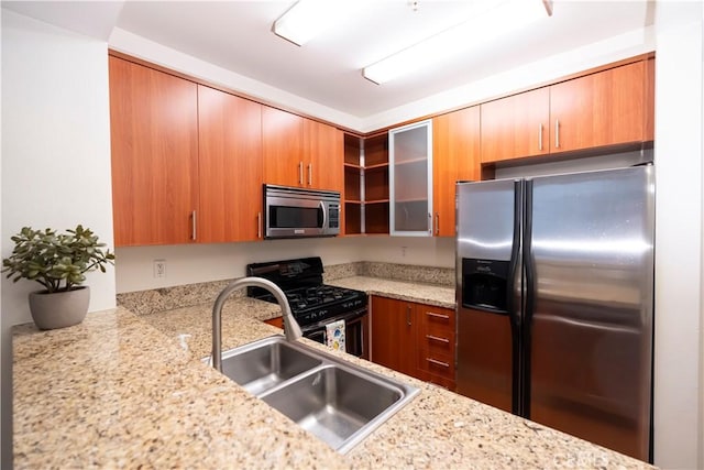 kitchen with kitchen peninsula, light stone counters, sink, and appliances with stainless steel finishes