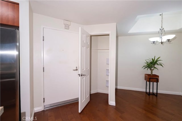 interior space featuring stainless steel fridge, dark hardwood / wood-style floors, and an inviting chandelier