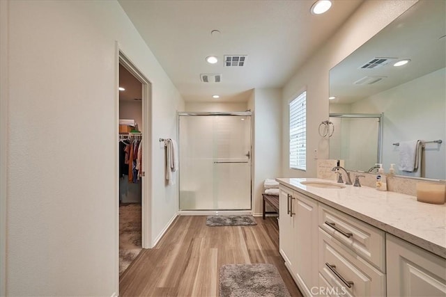 bathroom featuring hardwood / wood-style floors, vanity, and a shower with shower door