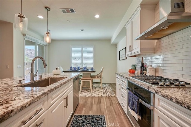 kitchen with wall chimney exhaust hood, light hardwood / wood-style floors, white cabinetry, and sink