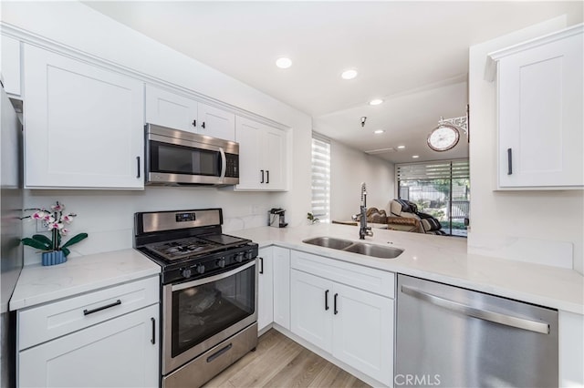 kitchen with white cabinetry, light stone countertops, light hardwood / wood-style flooring, sink, and stainless steel appliances