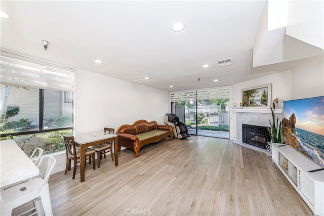 living room featuring light hardwood / wood-style floors, a premium fireplace, and plenty of natural light