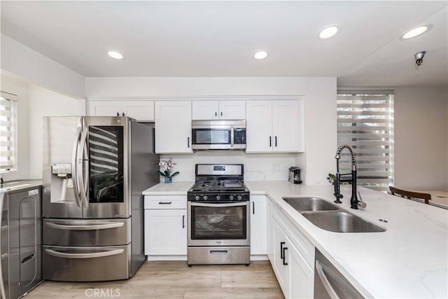 kitchen with sink, appliances with stainless steel finishes, light hardwood / wood-style flooring, and white cabinets