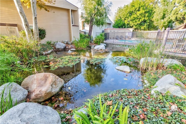 view of yard with a fenced in pool and a small pond