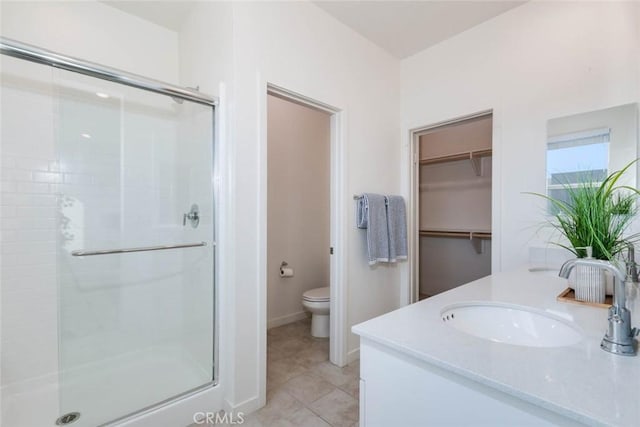 bathroom featuring tile patterned flooring, vanity, a shower with shower door, and toilet