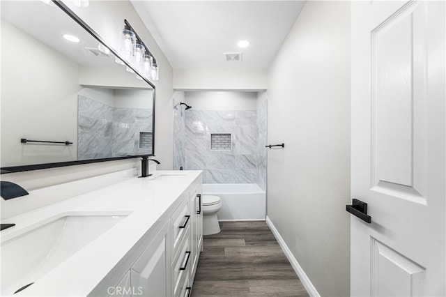 full bathroom with tiled shower / bath, vanity, hardwood / wood-style flooring, and toilet