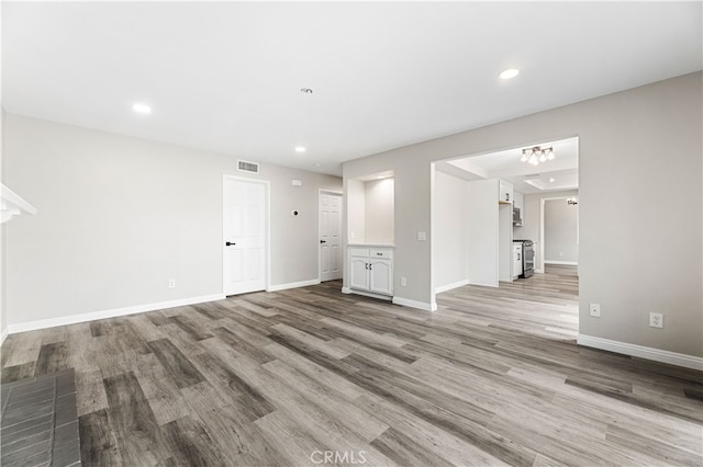 unfurnished living room with a chandelier and light wood-type flooring