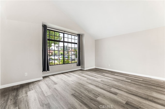 unfurnished room featuring vaulted ceiling and light hardwood / wood-style flooring