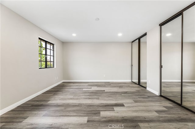 unfurnished bedroom with multiple closets and hardwood / wood-style floors