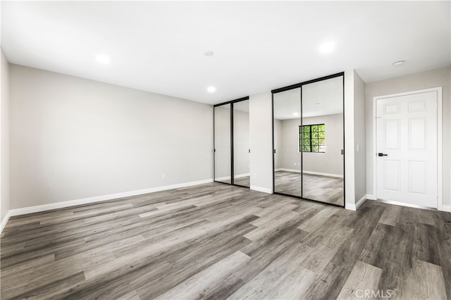 unfurnished bedroom with hardwood / wood-style floors and two closets