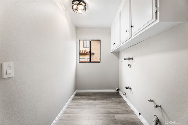 clothes washing area with light hardwood / wood-style flooring, hookup for a gas dryer, and cabinets