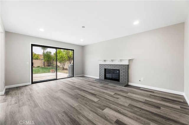 unfurnished living room with hardwood / wood-style flooring and a brick fireplace