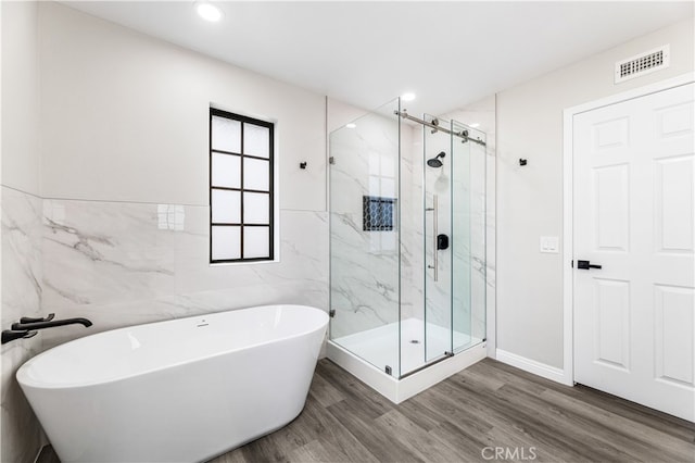 bathroom with tile walls, hardwood / wood-style flooring, and separate shower and tub