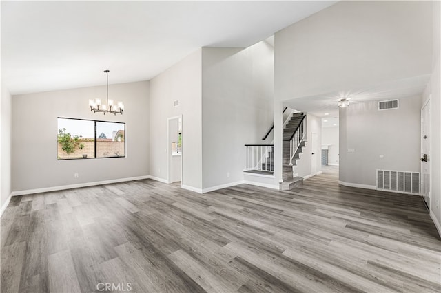 unfurnished living room with hardwood / wood-style floors, a chandelier, and high vaulted ceiling