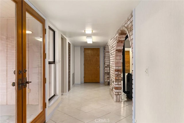 hallway with light tile patterned flooring and brick wall