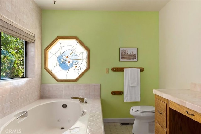 bathroom featuring tile patterned floors, vanity, a relaxing tiled tub, and toilet