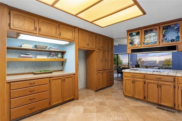 kitchen featuring cooktop, tile countertops, and light tile patterned flooring