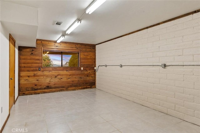 bathroom featuring tile patterned flooring, wood walls, and brick wall