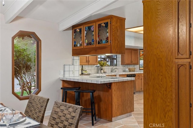 kitchen featuring decorative backsplash, light tile patterned floors, tile counters, a kitchen bar, and kitchen peninsula