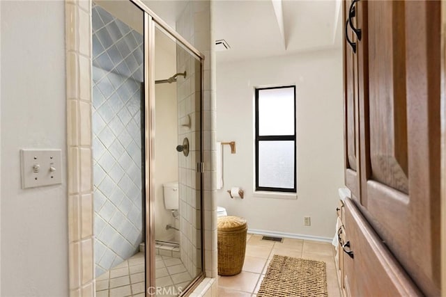 bathroom featuring tile patterned flooring, toilet, and walk in shower