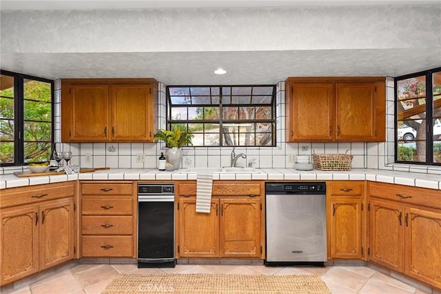 kitchen with stainless steel dishwasher, a healthy amount of sunlight, and light tile patterned floors