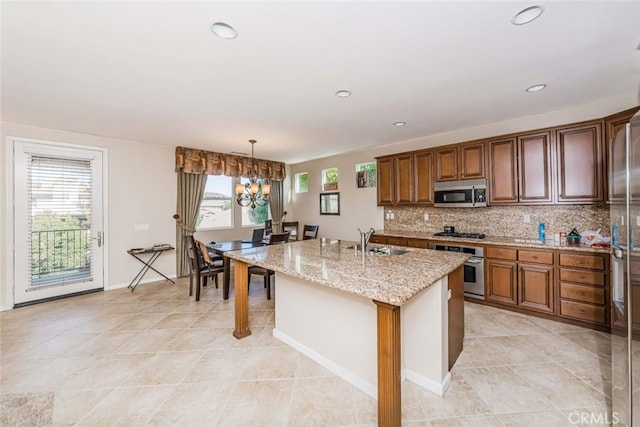 kitchen featuring a center island with sink, stainless steel appliances, sink, and a healthy amount of sunlight