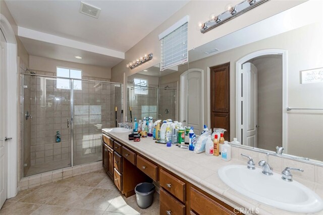 bathroom with tile patterned flooring, a shower with door, and vanity