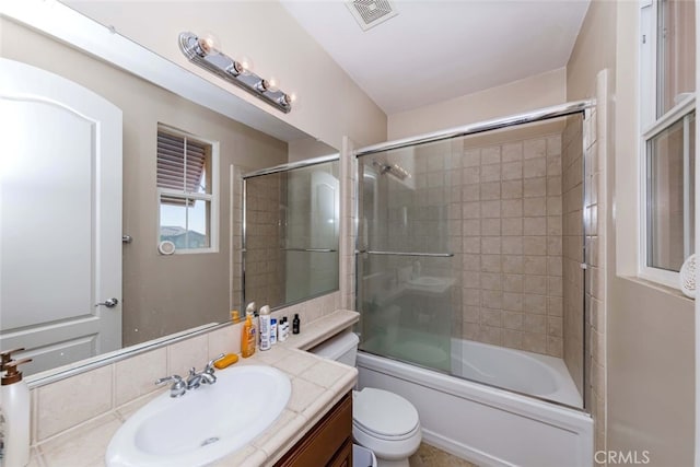 full bathroom featuring shower / bath combination with glass door, vanity, and toilet