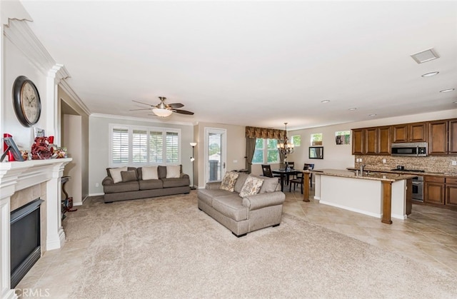 carpeted living room featuring ceiling fan with notable chandelier, crown molding, and a healthy amount of sunlight