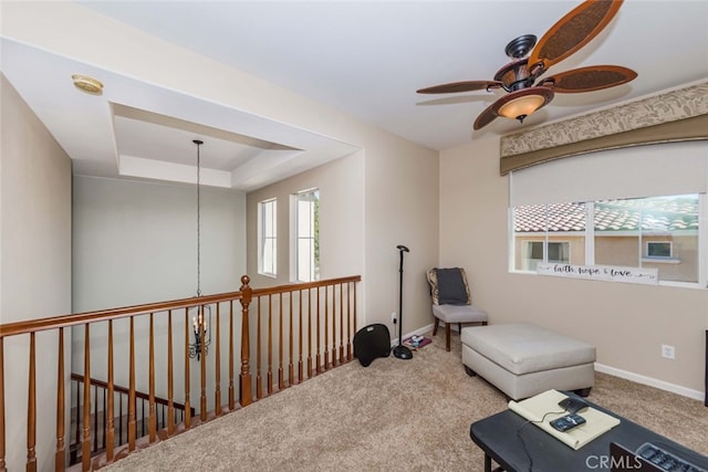 sitting room featuring a tray ceiling, carpet, and ceiling fan