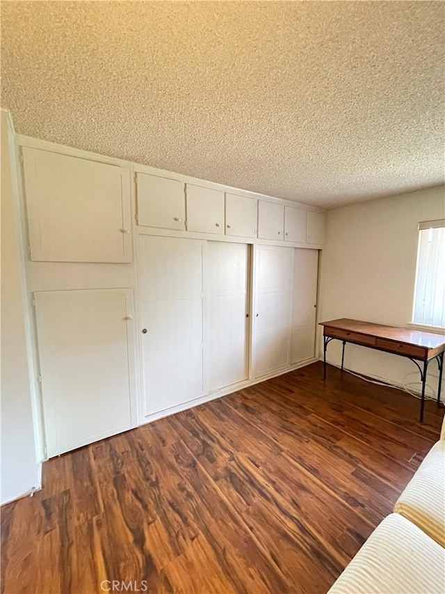 unfurnished bedroom featuring a closet, dark hardwood / wood-style flooring, and a textured ceiling