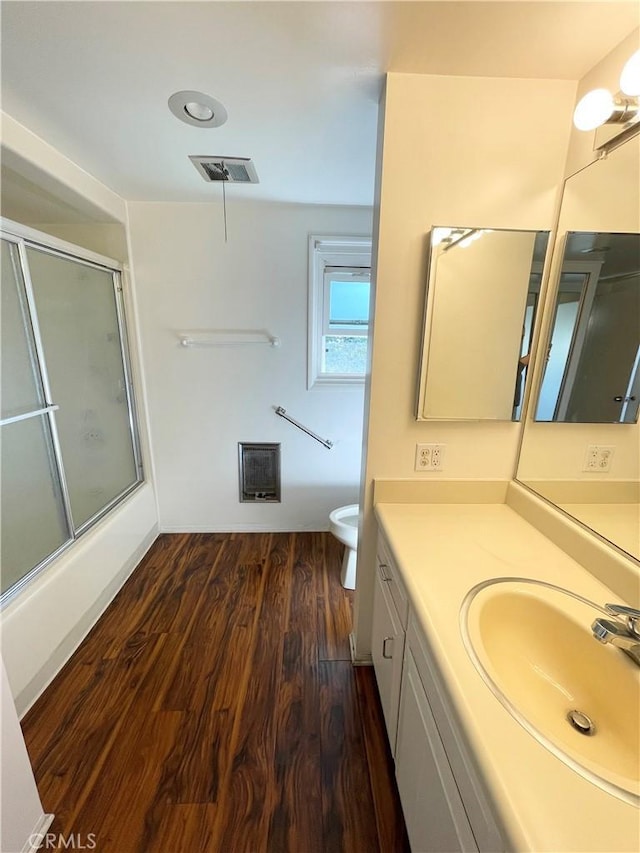 bathroom featuring toilet, vanity, a shower with door, and hardwood / wood-style flooring