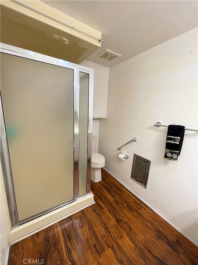 bathroom featuring a shower with shower door, toilet, and wood-type flooring