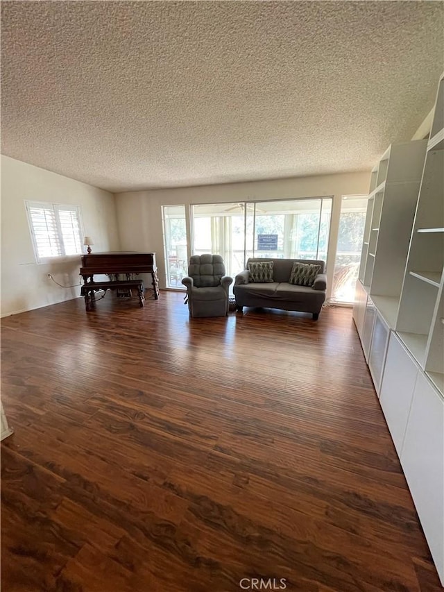 unfurnished living room with dark hardwood / wood-style flooring and a textured ceiling