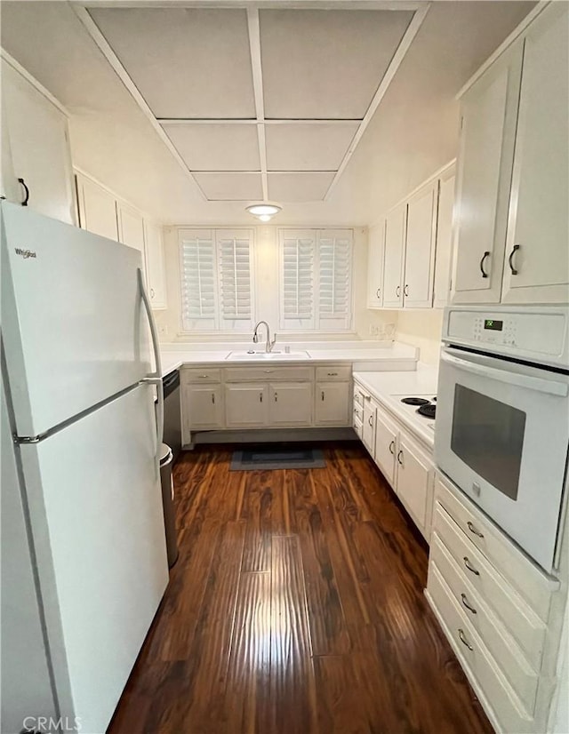 kitchen featuring white appliances, white cabinetry, dark wood-type flooring, and sink