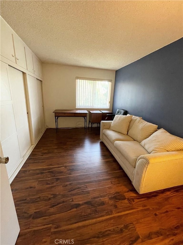 living room with a textured ceiling and dark hardwood / wood-style floors