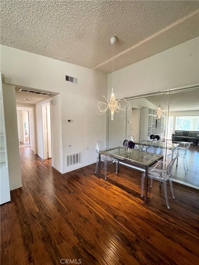 unfurnished dining area with a chandelier, a textured ceiling, and dark hardwood / wood-style flooring