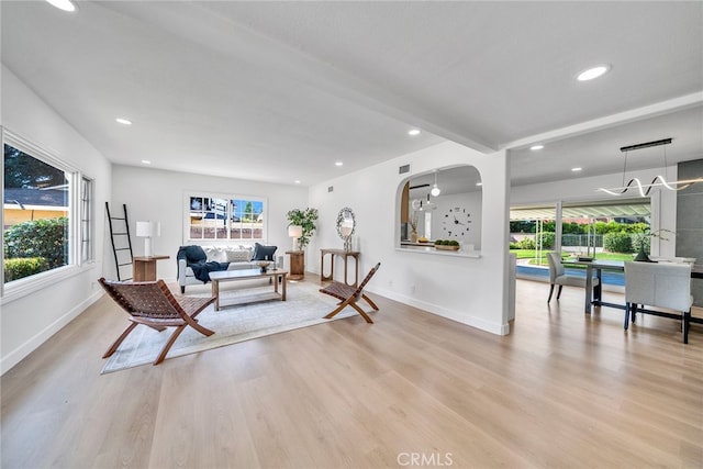 living room featuring beamed ceiling and light hardwood / wood-style flooring