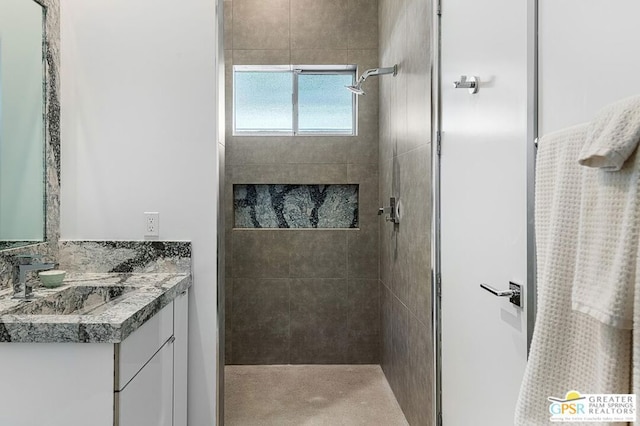 bathroom with a tile shower and vanity