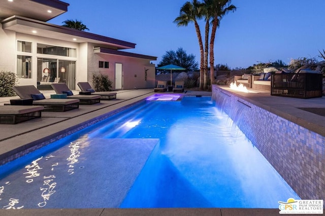 pool at dusk with a patio and pool water feature