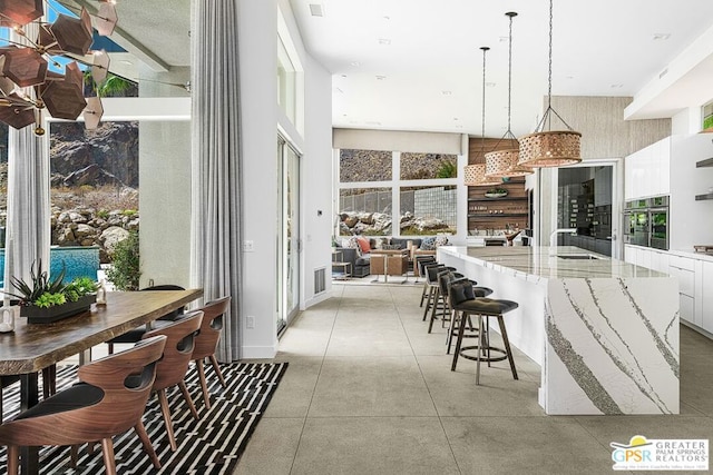 kitchen featuring hanging light fixtures, sink, plenty of natural light, white cabinetry, and stainless steel oven