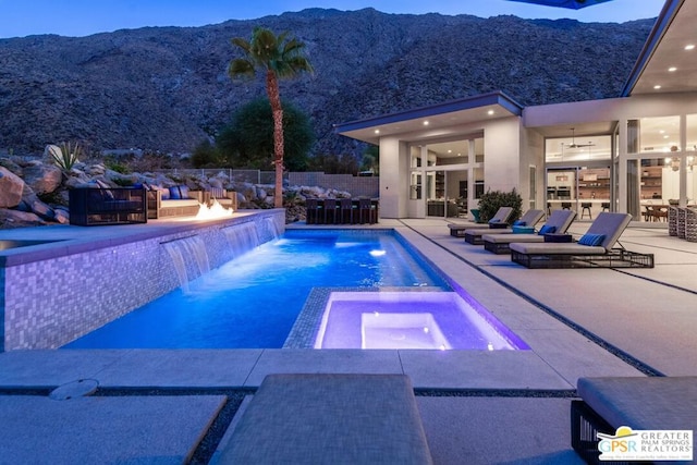 view of swimming pool with an in ground hot tub, a mountain view, pool water feature, and a patio area