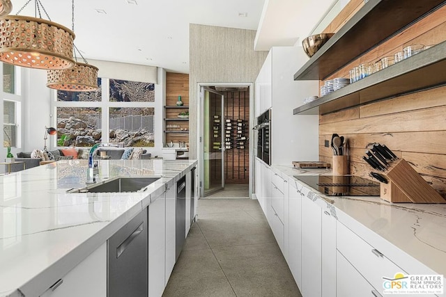 kitchen with hanging light fixtures, light stone counters, white cabinetry, and appliances with stainless steel finishes