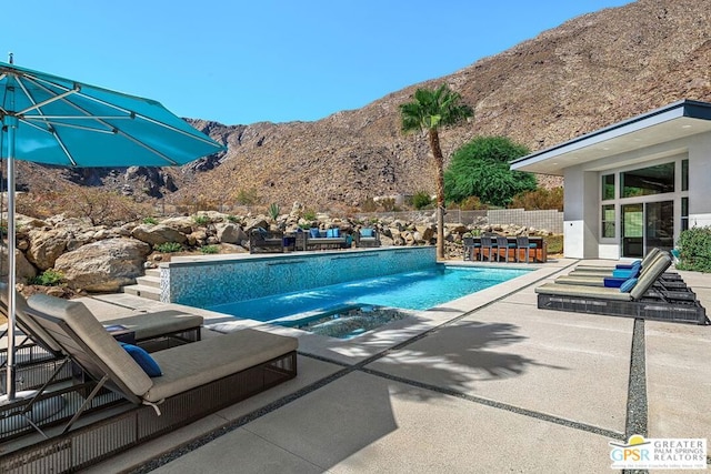 view of swimming pool featuring an in ground hot tub, a mountain view, and a patio area