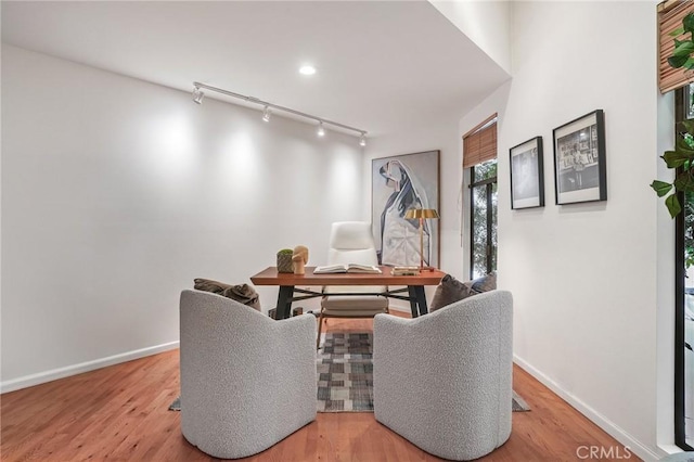 dining space with track lighting, baseboards, and wood finished floors